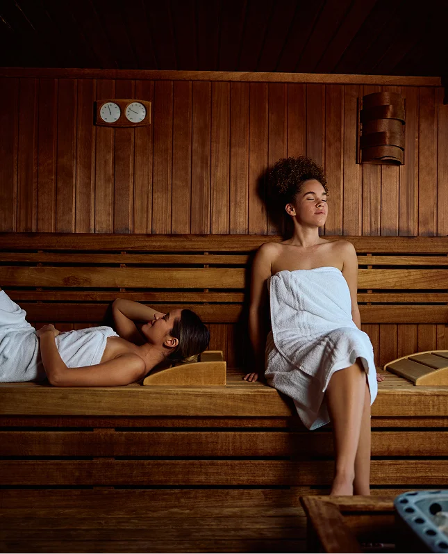 Zwei Frauen entspannen in einer modern gestalteten Holzsauna.